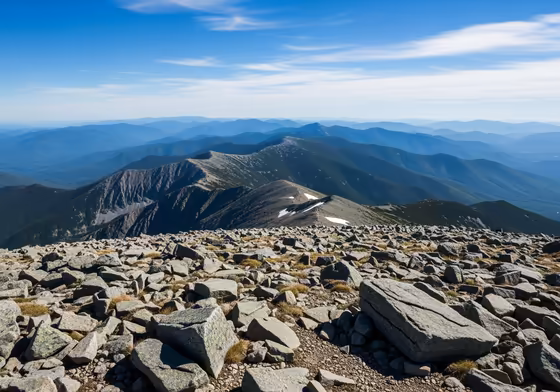 Panoramic view from the summit of Mount Washington on a clear day, overlooking the vast expanse of the White Mountains.